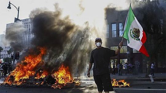 LA 다운타운에서 한 남성이 불타는 차량 옆에서 멕시코 국기를 흔들고 있습니다. EPA 연합뉴스